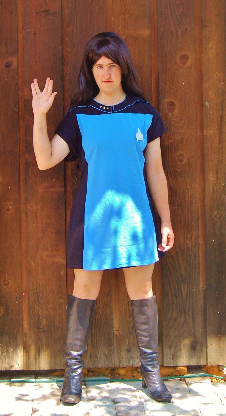 a woman standing in front of a wooden fence with her hand up to the side