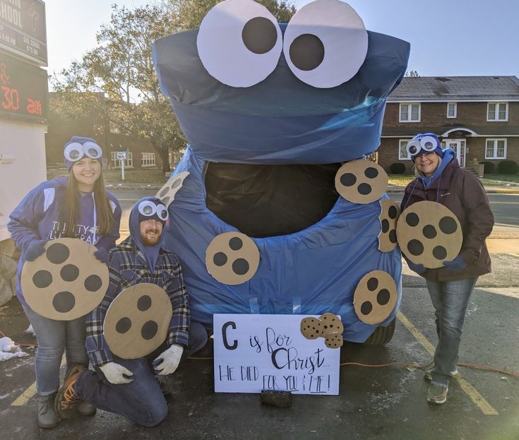 three people standing next to an inflatable blue object with googly eyes on it