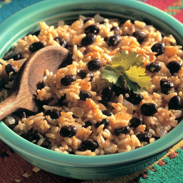 a blue bowl filled with rice and olives on top of a colorful table cloth