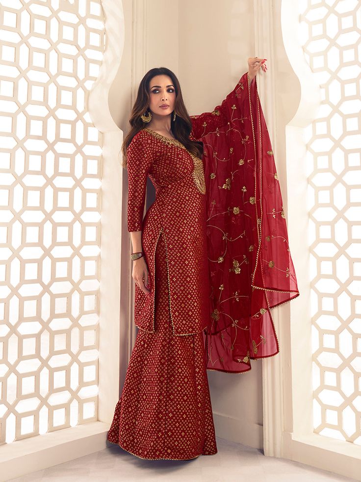 This Malaika Arora Maroon Zari Woven Yoke Design Embroidered Straight Kurta set features true craftsmanship in a luxurious silk blend design. Embellished with intricate Zari, this sharara is perfect for ethnic events and winter parties. Ready-to-wear, it features a round neck and three-quarter sleeves, with side slits for extra comfort. Grandeur and majestic artwork is attributed to this exquisite creation by Malaika Arora. TOP: Silk Blend(Brocade), TOP INNER: Cotton, BOTTOM: Silk Blend(Brocade) Semi-stitched Banarasi Silk Sharara With Dabka Work, Festive Semi-stitched Straight Kurta Salwar Kameez, Unstitched Embroidered Palazzo Set In Dola Silk, Unstitched Resham Embroidered Kurta, Semi-stitched Bollywood Salwar Kameez With Zari Work, Festive Designer Semi-stitched Salwar Kameez, Floor-length Embroidered Salwar Kameez For Diwali, Unstitched Bollywood Festive Sets, Floor-length Resham Embroidered Salwar Kameez For Diwali