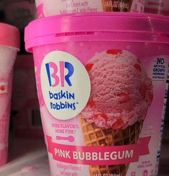 pink bubblegum ice cream is on display in a store, with two cups behind it