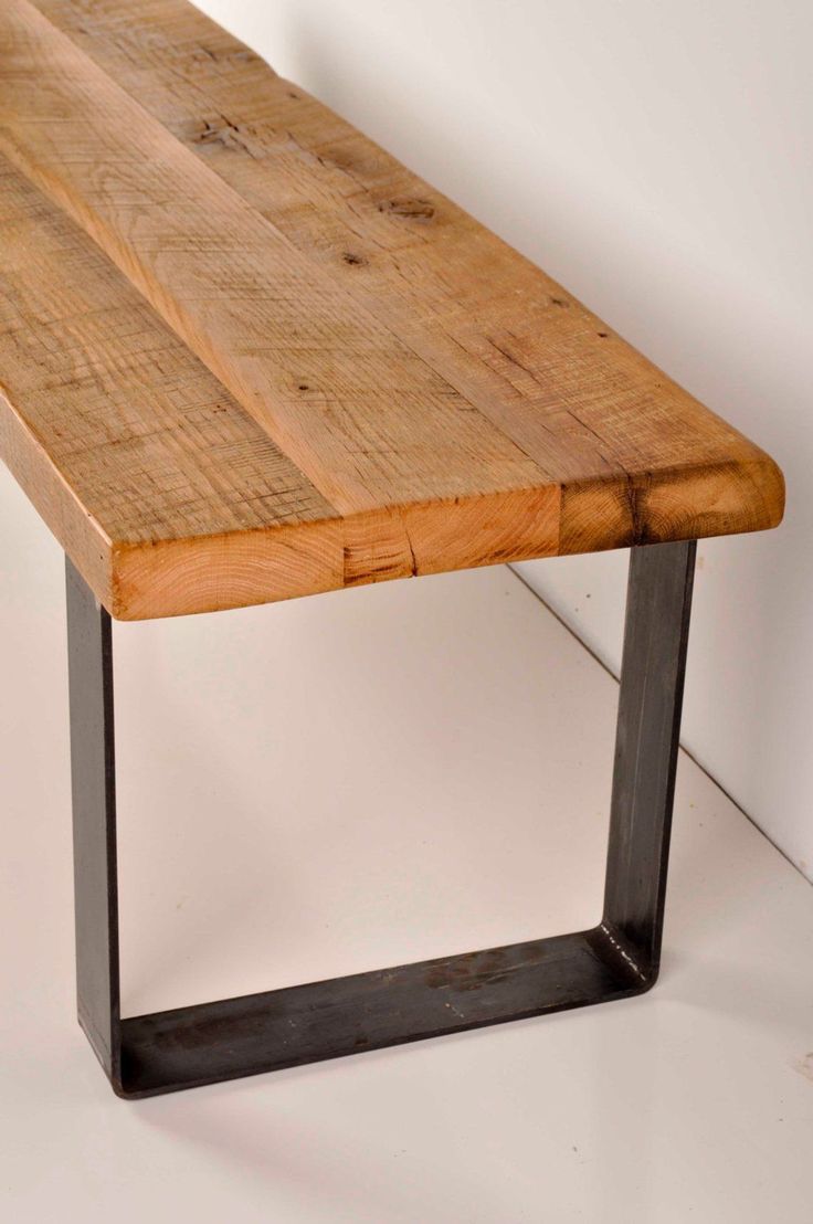 a wooden bench sitting on top of a white floor next to a metal frame wall