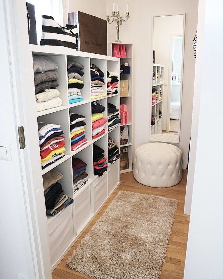 a walk in closet with white shelving and lots of clothes on the shelfs