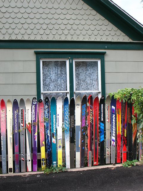 many skis are lined up in front of a house with a green door and window