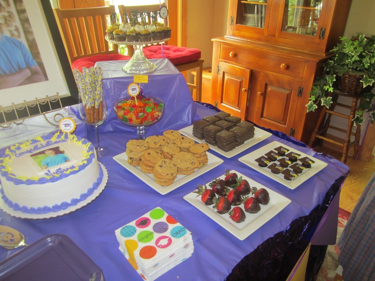 a table topped with cakes and desserts on top of blue cloth covered tablescloth