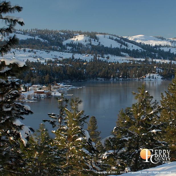 a lake surrounded by trees and snow covered mountains