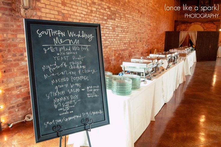 a long table is set up with food and drinks for a wedding reception at the brick building