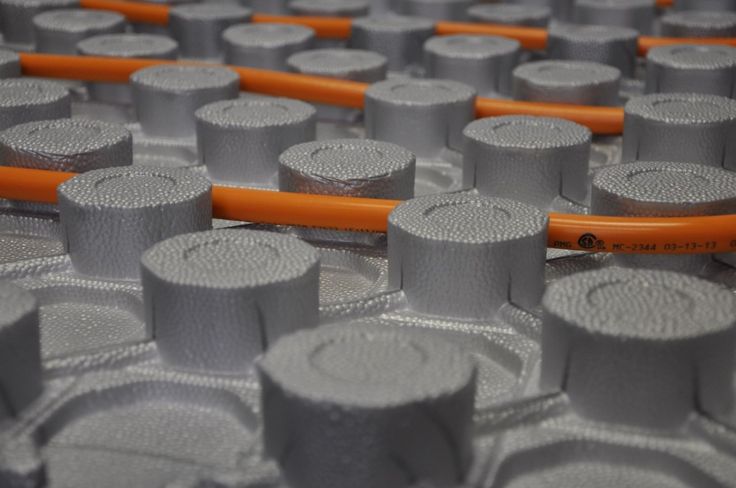 many rolls of toilet paper sitting on top of each other in an assembly line with orange handles