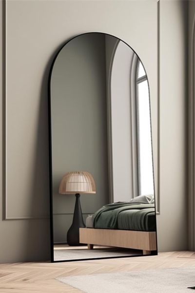 a large mirror sitting on top of a wooden floor next to a bed in a room