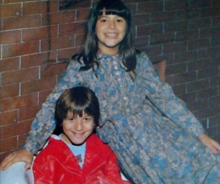 an old photo of two young children in front of a brick wall