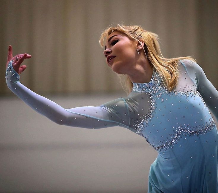 a woman in a blue leotard holding her arms out