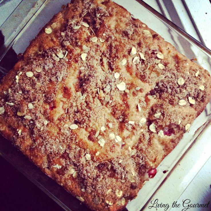 a square cake sitting on top of a pan covered in nuts and cranberries