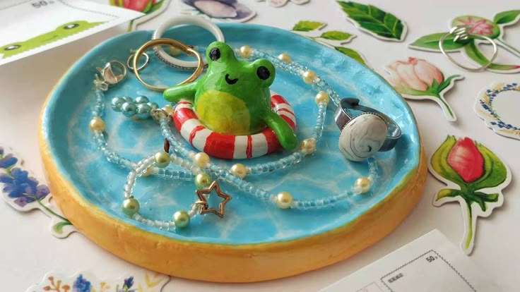 a green frog in a red and white life preserver on a blue plate with pearls