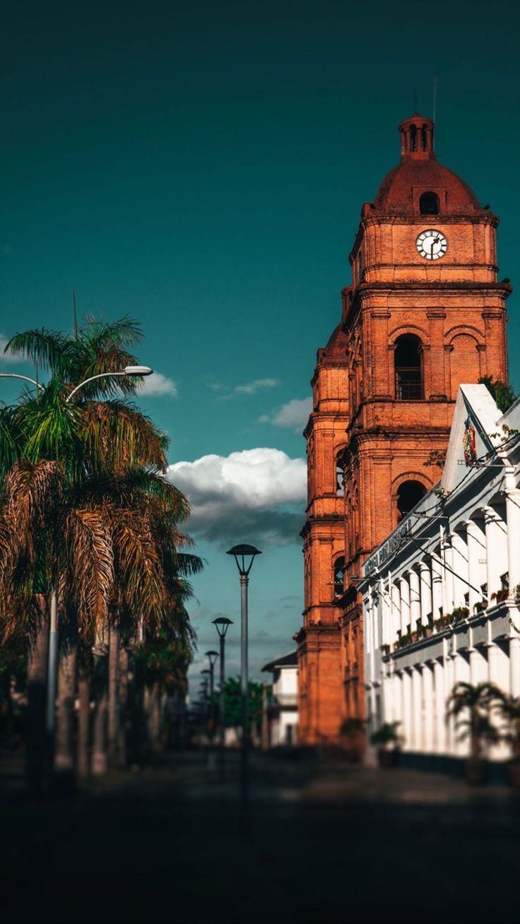 a tall tower with a clock on it's side next to trees and buildings