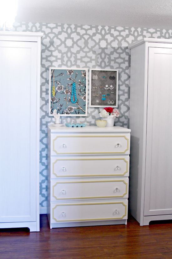 a white dresser sitting next to a wall with pictures on it