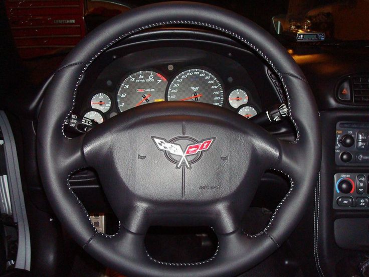 the interior of a car with steering wheel and gauges