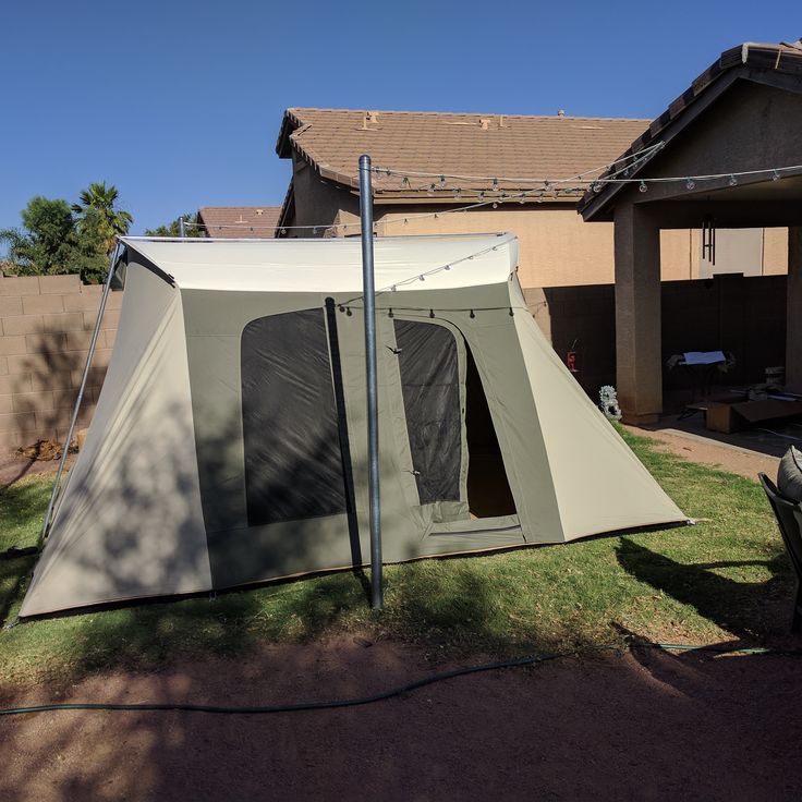 a tent set up in front of a house with the door open and windows closed