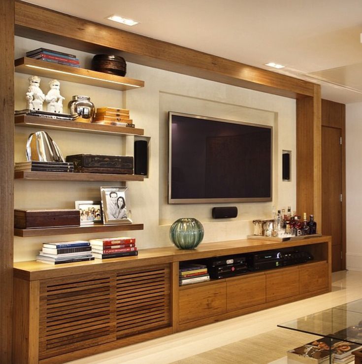 a living room with wooden shelves and a flat screen tv mounted on it's wall