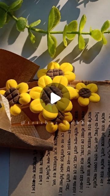 yellow flowers are sitting on top of an old book and some leaves in the background