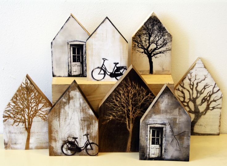 small wooden houses with trees and bicycles on them are displayed in front of a white wall