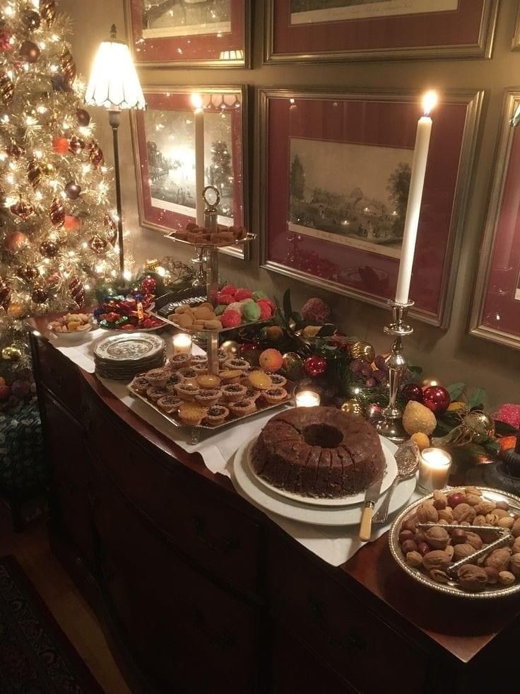 a table topped with cakes and desserts next to a christmas tree covered in lights