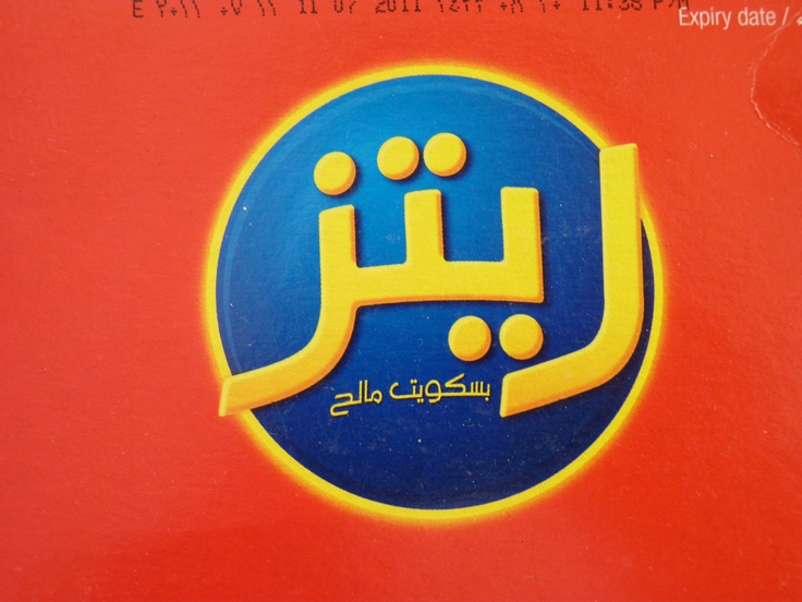 an arabic sign on the side of a red wall with blue and yellow lettering in two languages