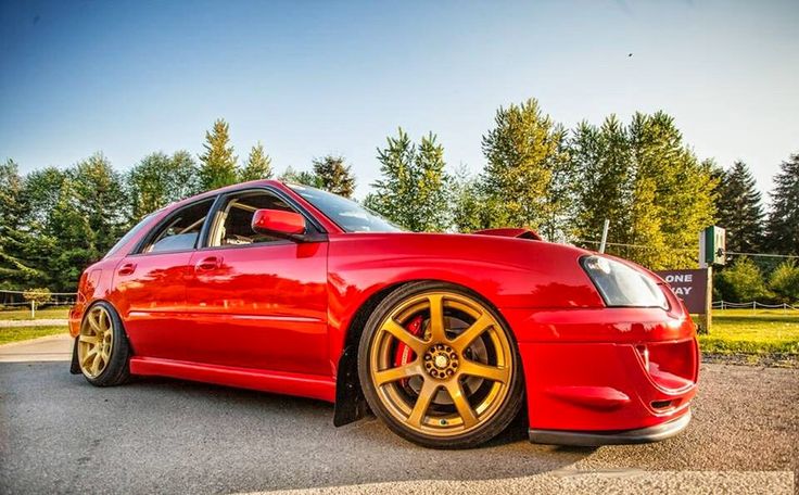 a red car parked in front of some trees