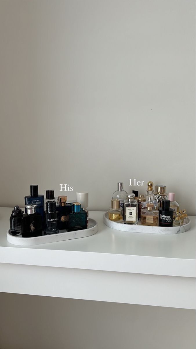 two trays with perfume bottles on top of a white shelf next to each other