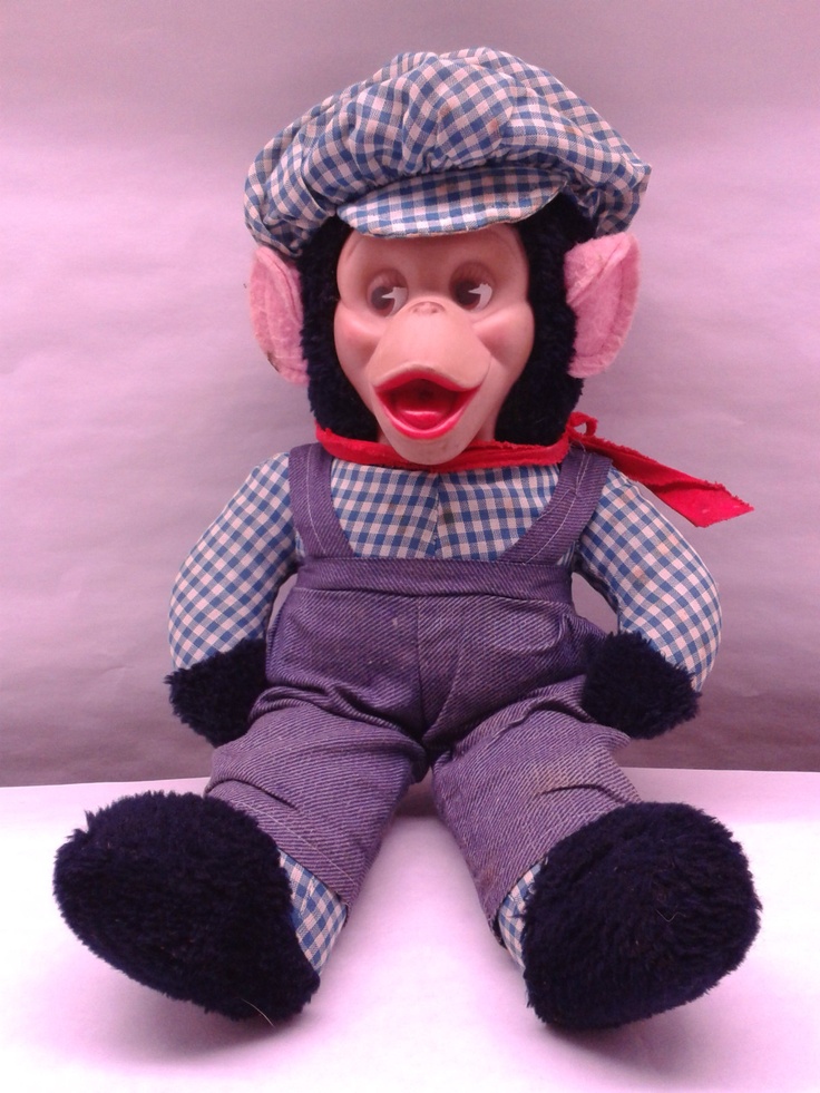 a stuffed monkey wearing overalls and a hat on top of a white countertop