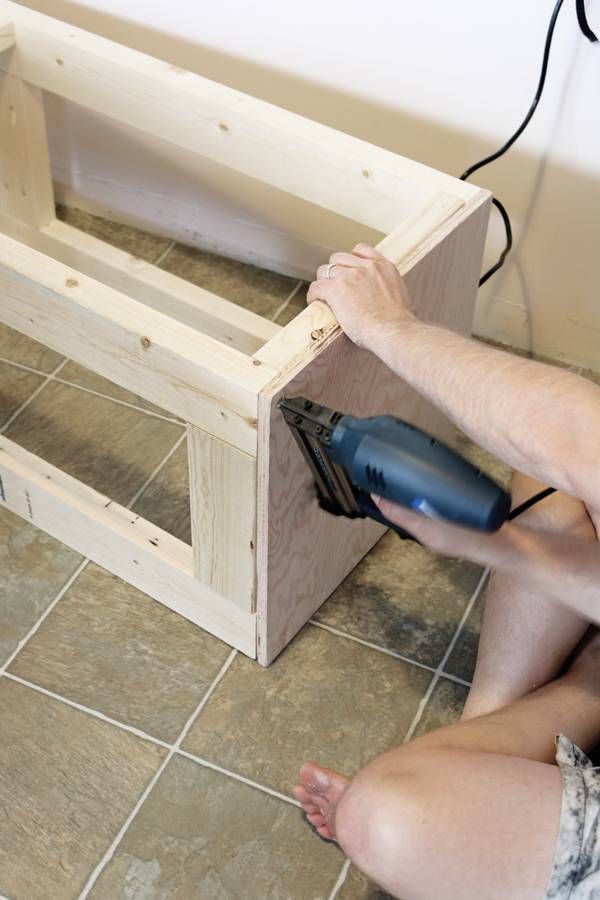 a man using a power drill to attach the top of a wooden box on the floor