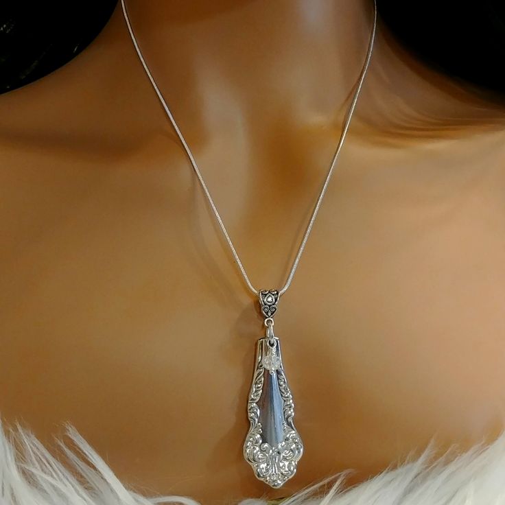 a woman's torso wearing a white feathered dress with a pendant on it