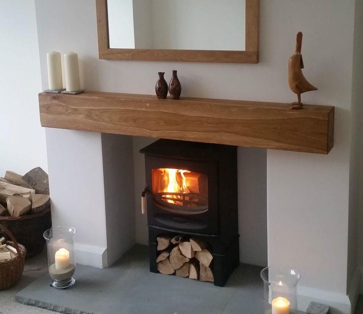 a wood burning stove in a living room next to a mirror and firewood logs