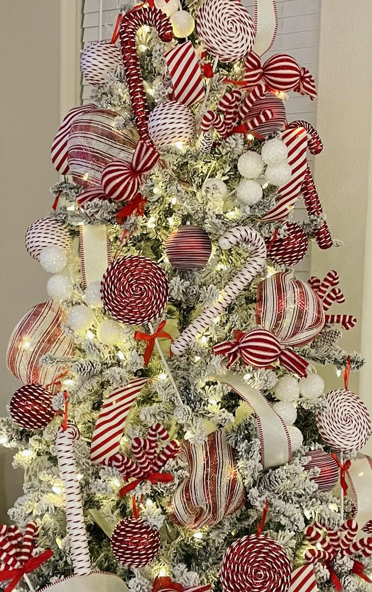 a christmas tree decorated with red and white lollipops, candy canes and bows