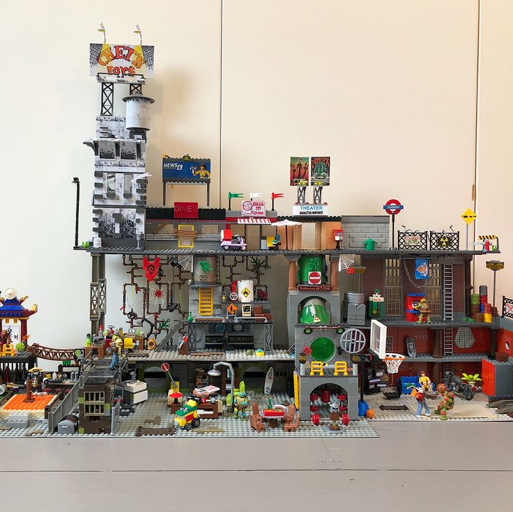 a lego model of a building with lots of toys on it's sides and people standing in front of it