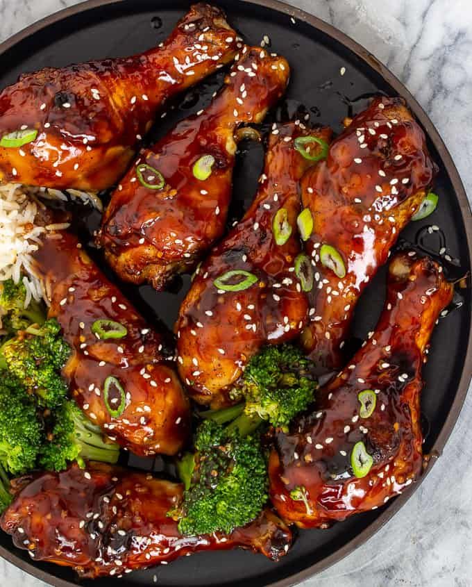 chicken wings with broccoli, rice and sesame seeds in a black bowl on a marble surface