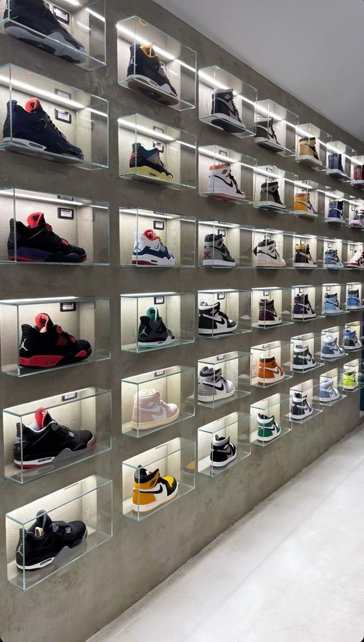 there are many different shoes on display in the store's glass shelves with lights above them