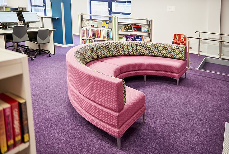 a pink couch sitting on top of a purple floor in a room filled with books