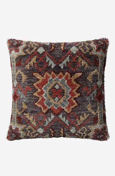 a brown and red pillow with an ornate design on the front, sitting on a white background