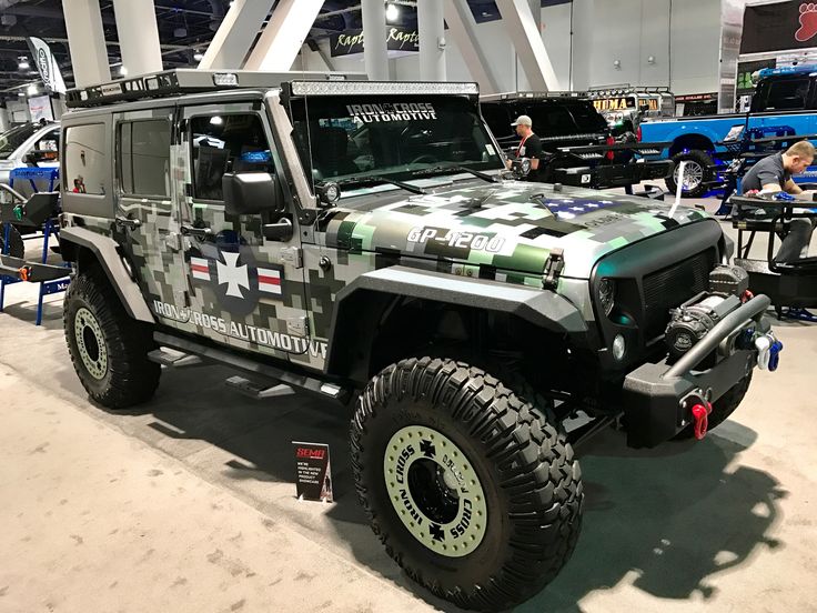 a camouflage jeep is on display at an auto show