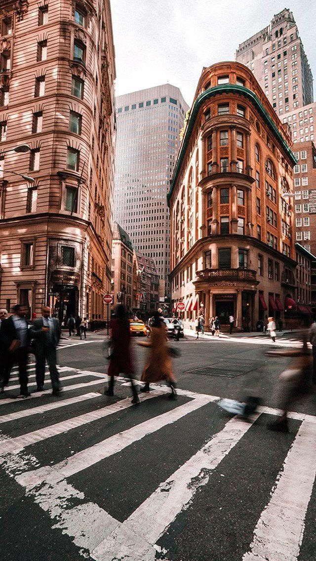 people crossing the street in front of tall buildings