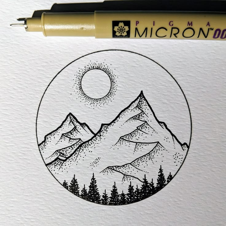 a pen is sitting on top of a piece of paper with a drawing of mountains