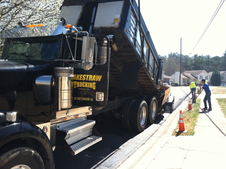 two men standing next to a black dump truck