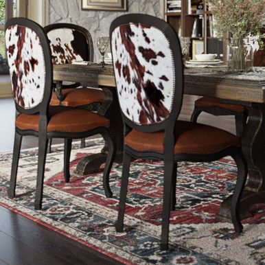 the dining room table is decorated with cow hide chairs and an area rug in front of it