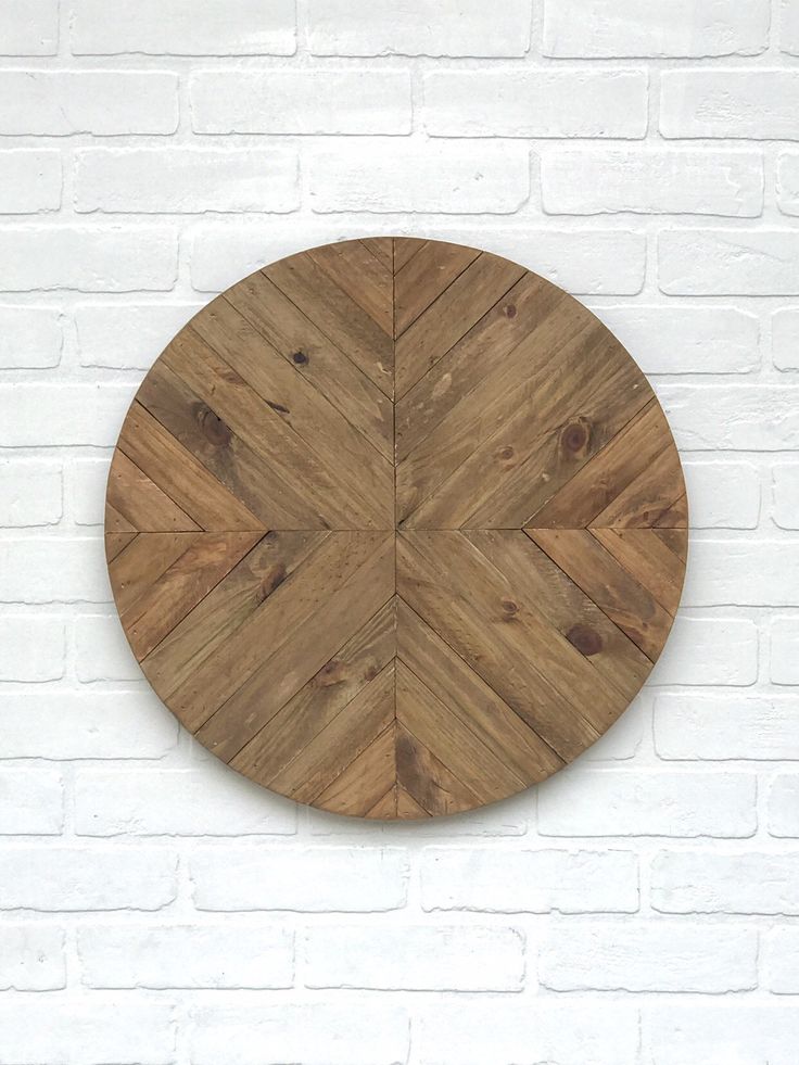 a round wooden cutting board sitting on top of a white brick wall