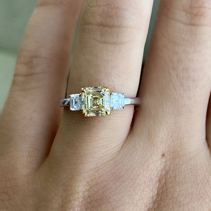 a woman's hand with a yellow and white diamond ring on top of it