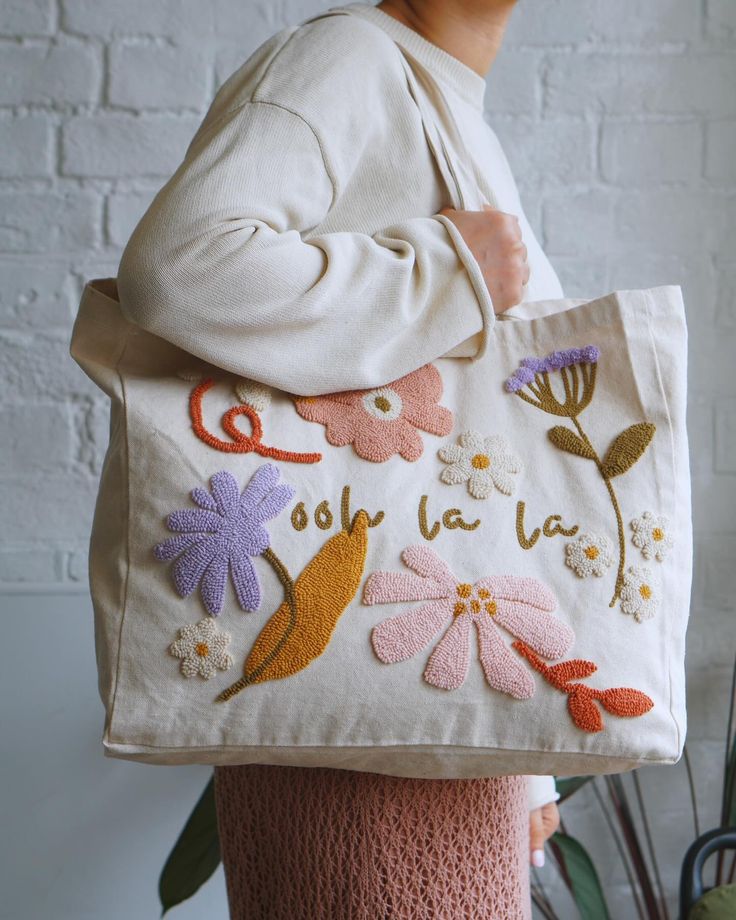 a woman carrying a bag with embroidered flowers on it