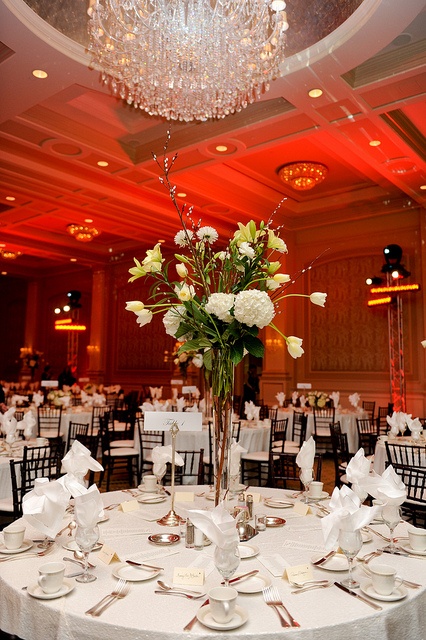 a table set up for a formal function with flowers in vases and place settings