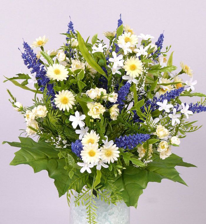 a vase filled with lots of white and blue flowers