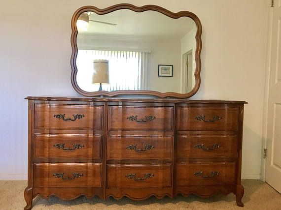 a large wooden dresser sitting in front of a mirror with a lamp on top of it