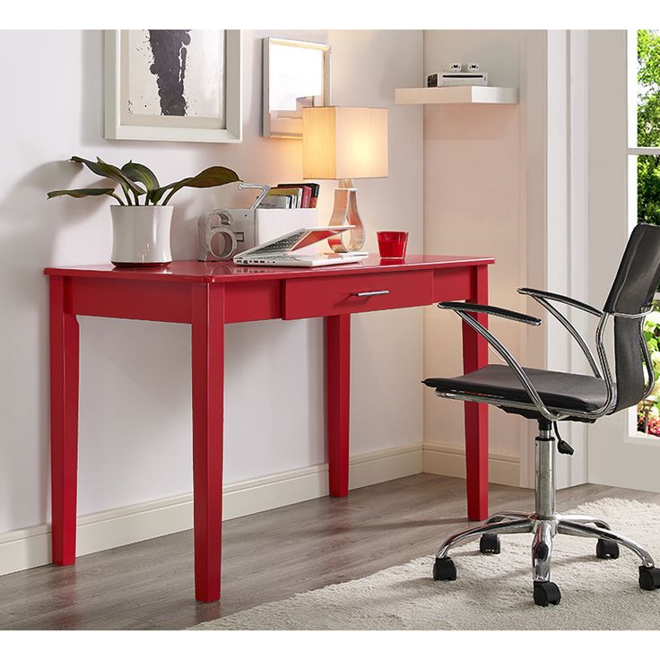 a red desk with a computer chair next to it and a potted plant on top